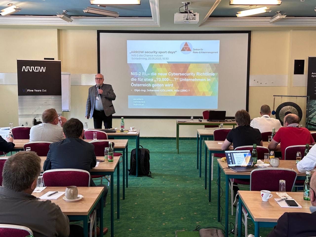 Referent präsentiert Cybersecurity-Richtlinien auf Konferenz vor Publikum im Seminarraum