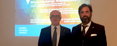 Zwei Männer in Business-Kleidung stehen vor einer Präsentationsfläche mit blauem Workshop-Titel.