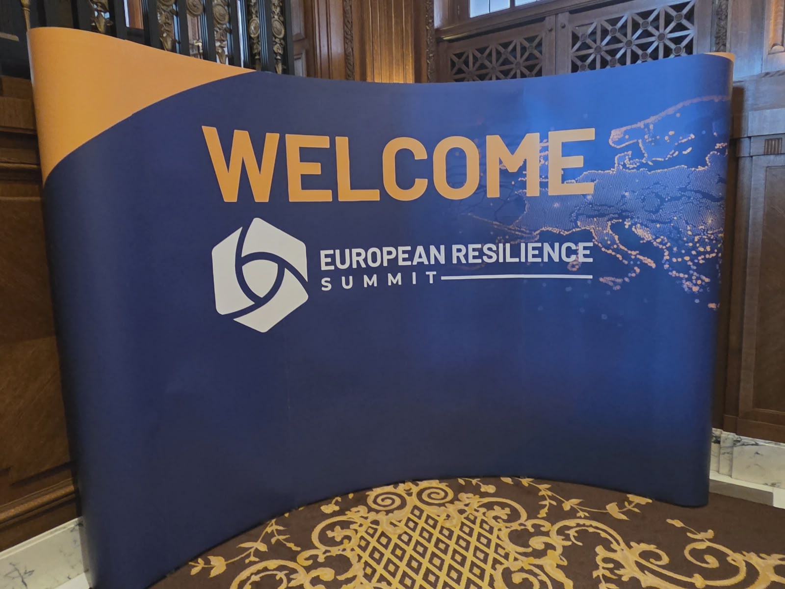 Willkommensschild zum European Resilience Summit mit blauem Hintergrund und Europakarte in historischem Gebäude